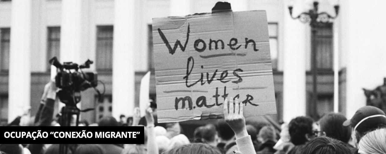 Fotografia retangular, em preto e branco, mostrando um cartaz escrito 'Women lives matter' em uma manifestação