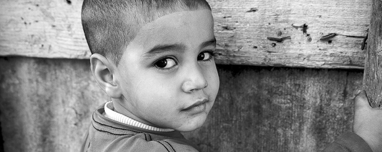 Em preto e branco, a imagem mostra um menino olhando de lado para a foto
